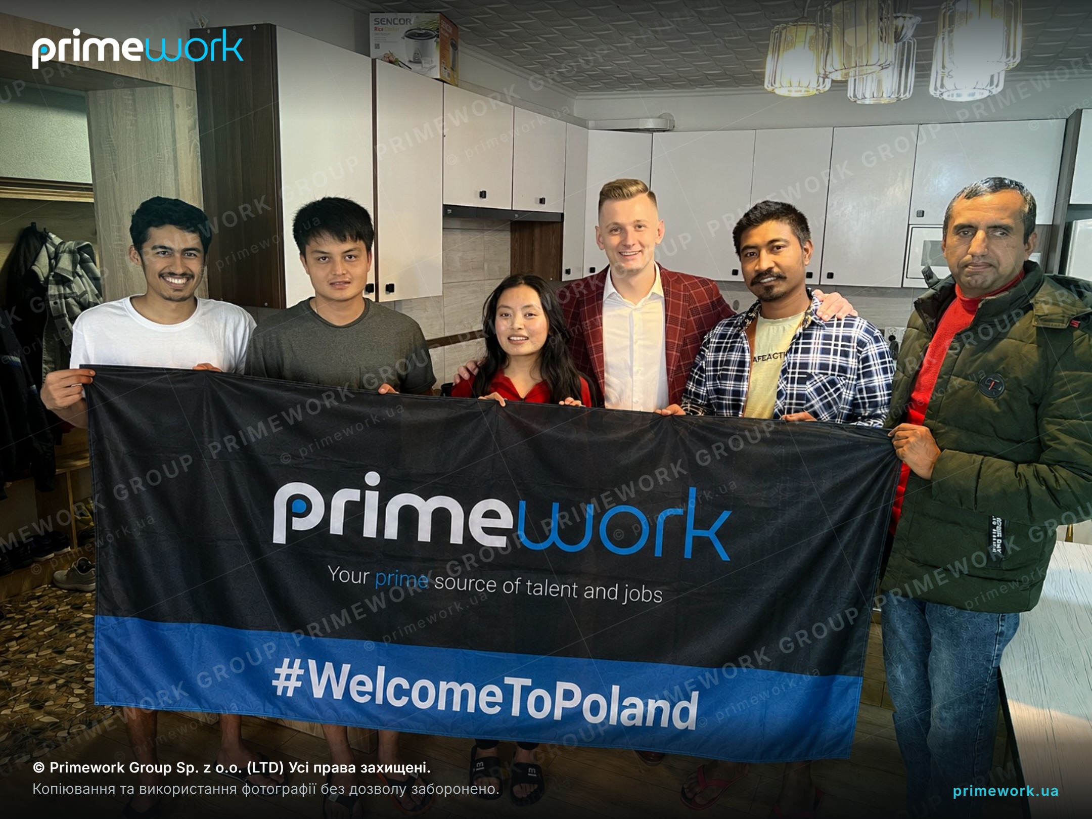 Працівники з-за кордону з банером Primework на обладнаній кухні робітничого помешкання